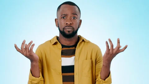 A man shrugging with both palms turned up, against a plain blue background